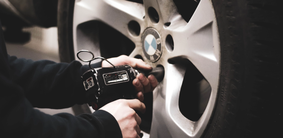 Człowiek z narzędziem wkręcający koło samochodowe